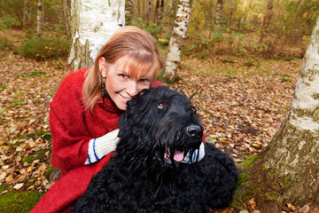 Wall Mural - Young woman in a red poncho and Black Russian Terrier dog in aut