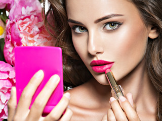 Wall Mural - woman applying lipstick looking at mirror