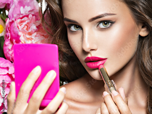 Fotografie, Obraz Woman applying lipstick looking at mirror
