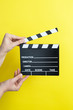 © Myvisuals - woman holding movie clapper on yellow background, cinema concept