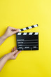 © Myvisuals - woman holding movie clapper on yellow background, cinema concept