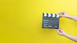 © Myvisuals - woman holding movie clapper on yellow background, cinema concept