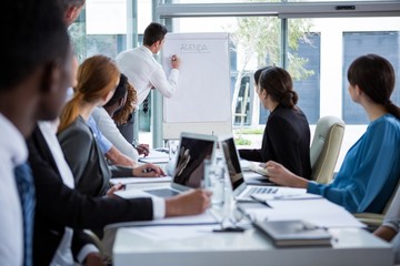 Businessman discussing on white board with coworkers