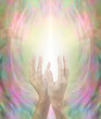 Beaming Beautiful Healing Energy - female hands held in gentlly cupped upright position with a stream of light streaming up on a golden pink and green background 
