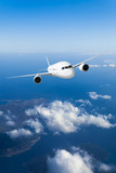 Fototapeta  - Podróż samolotem, samolot lecący w błękitnym niebie wysoko nad ziemią