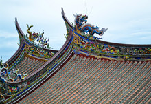 Chinese Temple Roofs. One Blue And One Yellow Dragon On Each Roof. Phoenix And Other Historical Characters Along The Edge Of The Roof All Painted In Red, Yellow, Blue, Green And White Colors.