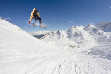 Wall Mural - Snowboarder jumping on mountains. Extreme snowboard freeride sport.