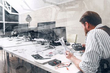 Toy repair shop, working late, double exposure. Manager in office constructing new electronic toy, drone renovation