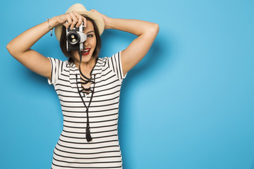 Fashion young girl makes the photo with old camera. Blue backgro