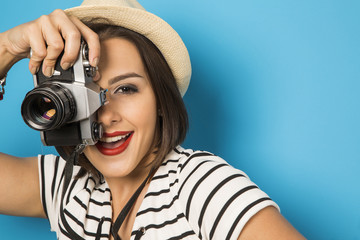 Wall Mural - Fashion young girl makes the photo with old camera. Blue backgro