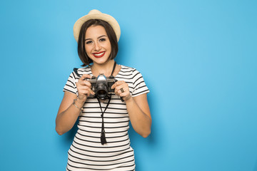 Wall Mural - Fashion young girl makes the photo with old camera. Blue backgro