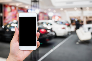 hand hold mobile phone with car showroom