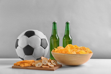 Wall Mural - Beer with snacks and football ball on light background