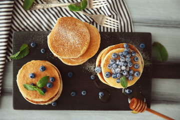 Wall Mural - Delicious pancakes with blueberries, honey and mint on wooden cutting board