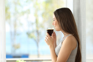 Canvas Print - Girl drinking coffee looking through a window