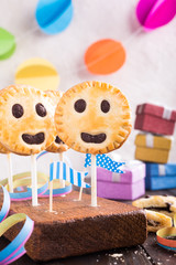 Wall Mural - Homemade shortbread smiley cookies with dark chocolate on stick called pie pops. Children's party background.