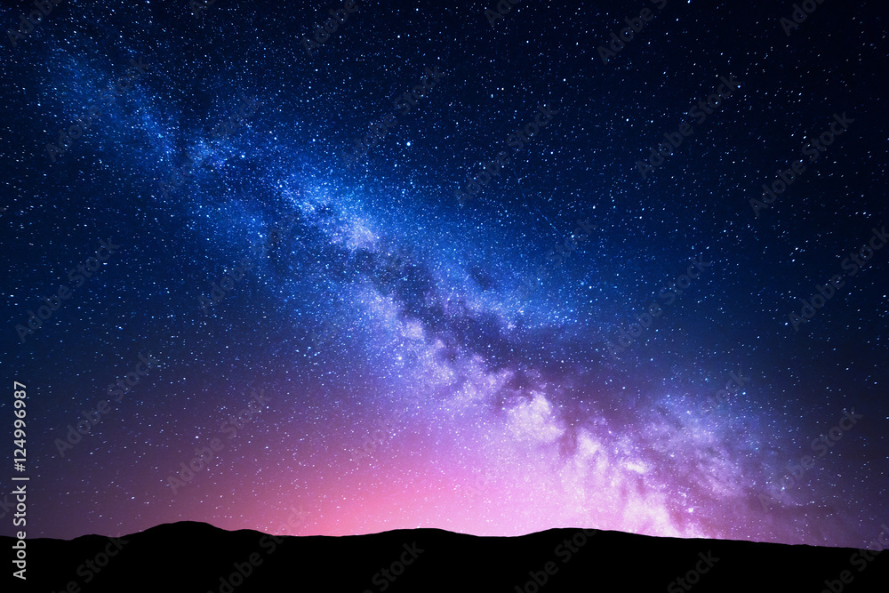 Milky Way and pink light at mountains. Night colorful landscape. Starry sky with hills at summer. Beautiful Universe. Space background with galaxy. Travel background - obrazy, fototapety, plakaty 