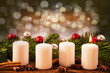 eine brennend Advent-Kerze vor Weihnachtsschmuck im Tannenzweig