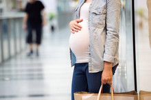 Unrecognizable Pregnant Woman Touching Her Belly, Holding Bags, 