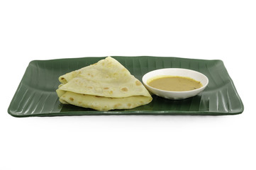 Two slices of homemade plain pancake with curry on green banana leaf plate on white background