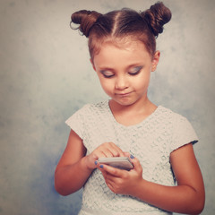 Cute kid girl with happy smile texting sms on mobile phone on bl