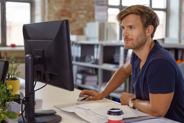 architekt sitzt am pc im büro mit bauplänen auf dem schreibtisch