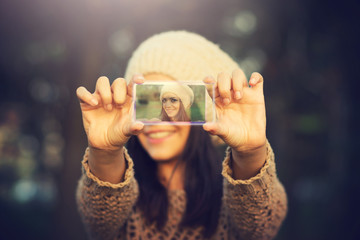 Young woman taking a selfie using futuristic transparent phone