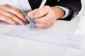 Person's Hand Signing Cheque