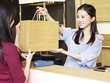 young asian female salesclerk handing merchandise to customer