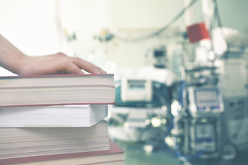 Wall Mural - Hand on the books against the background of medical equipment