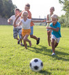 © JackF - Group of cheerful kids playing football together on green lawn i
