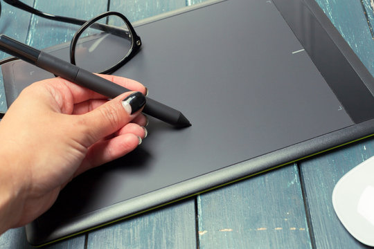 Hand of graphic designer working with stilus and tablet