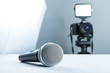 A wireless microphone lying on a studio table against the background of the DSLR camera to led light and softbox.