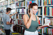© JackF - Cheerful  girl holding  book and talking on mobile phone