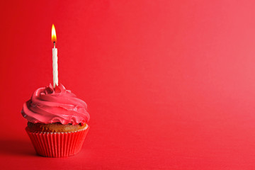 Wall Mural - Fresh tasty cupcake with candle on red background