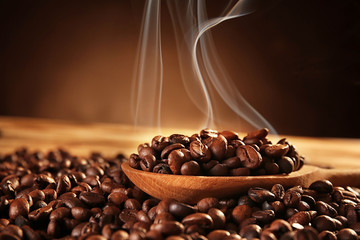 Canvas Print - Wooden spoon with roasted coffee beans on blurred background