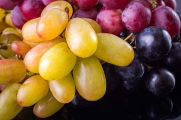 Wall Mural - Pink, white and black grapes. On a black background.