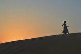 Fototapeta  - girl in the setting sun in the desert