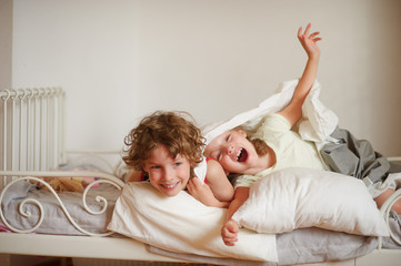 Two children, brother and sister, indulge on the bed in the bedroom.