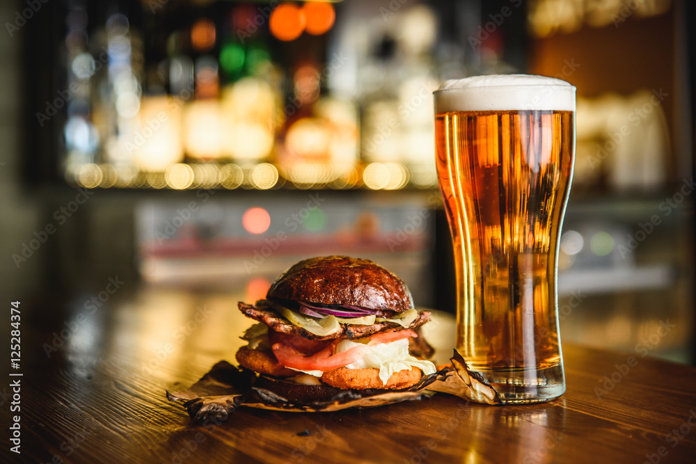 Hamburger and light beer on a pub background. - obrazy, fototapety, plakaty 