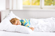 © Irina Schmidt - carefree little kid boy sleeping in bed in colorful nightwear.