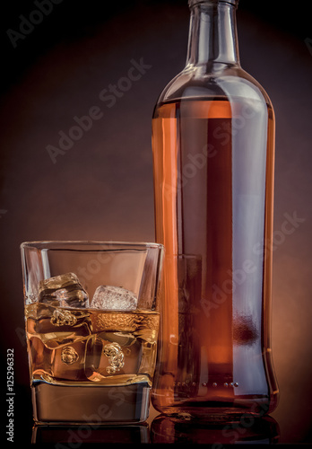 whisky-z-kostkami-lodu-w-szklanej-pobliskiej-butelce-na-czerni
