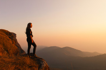 Hipster young girl with backpack enjoying sunset on peak of foggy mountain. Tourist traveler on background view mockup. Hiker looking sunlight in trip in Thailand country, mock up text.