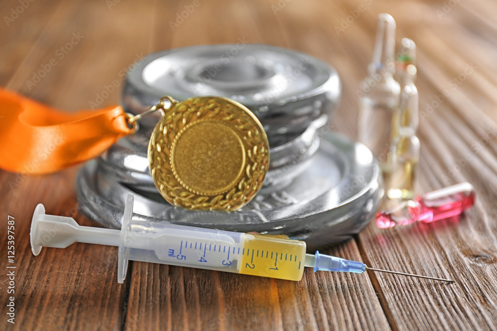 Syringe, medal and weight disks on wooden background