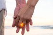 Couple holding hans at sunset time with engagement ring