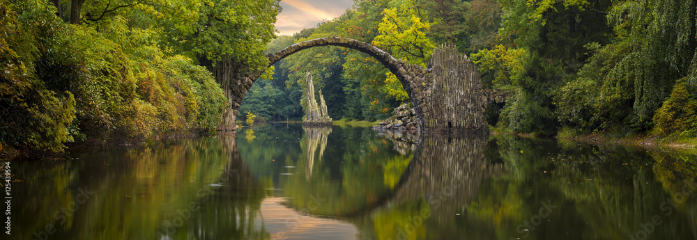 Autumn over Devil's bridge in the park Kromlau, Germany
 - obrazy, fototapety, plakaty 