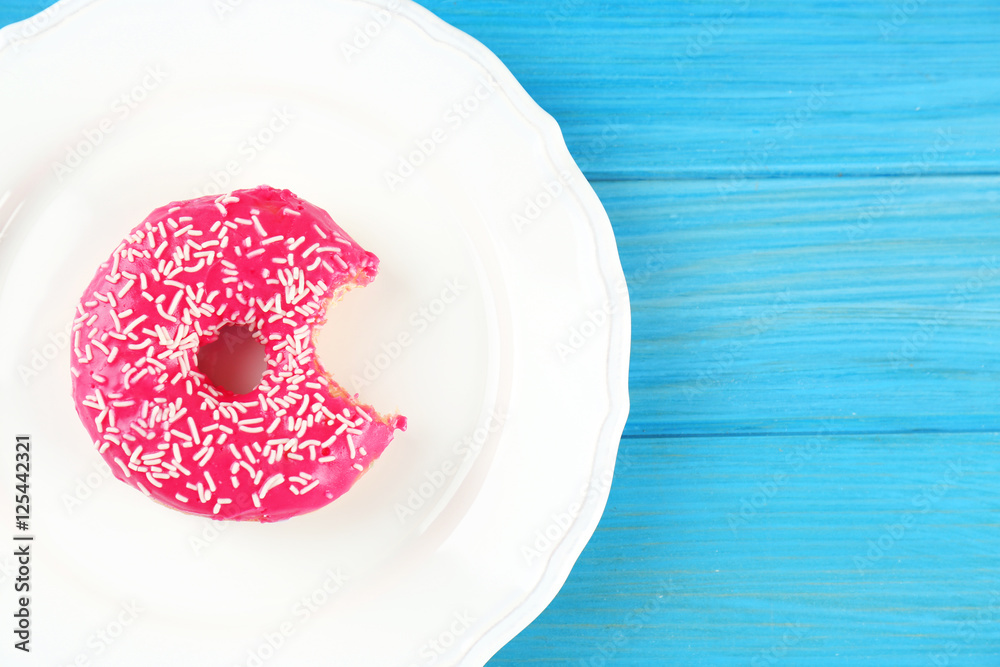 Plate with delicious donut on blue wooden background