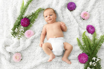 Poster - Cute baby lying on bedspread among flowers and fern leaves