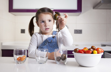 Little girl sorting by colors cherry tomatoes