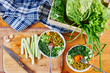 © amixstudio - Top view of vegetable mix in bowls with green peas, cucumbers, carrots, lettuce and dill, standing on a wooden table